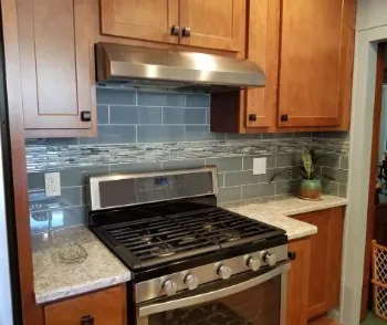 Glass subway tile kitchen backsplash behind a gas range
