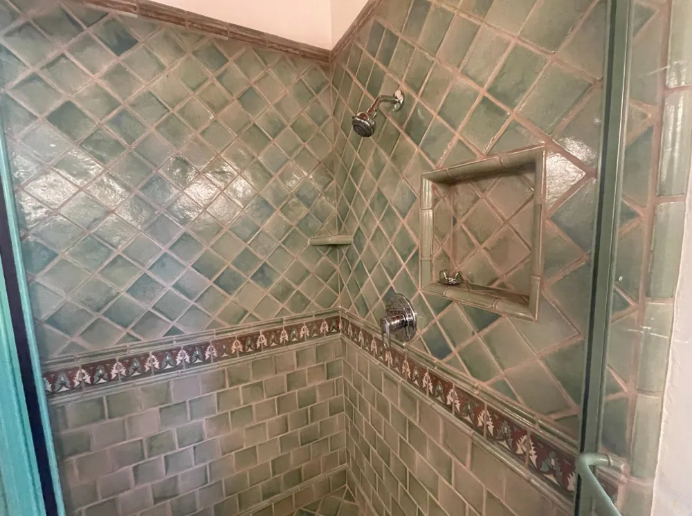 Custom shower with green diagonal ceramic tile and recessed niche