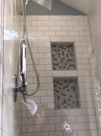 White subway tile shower with mosaic niches